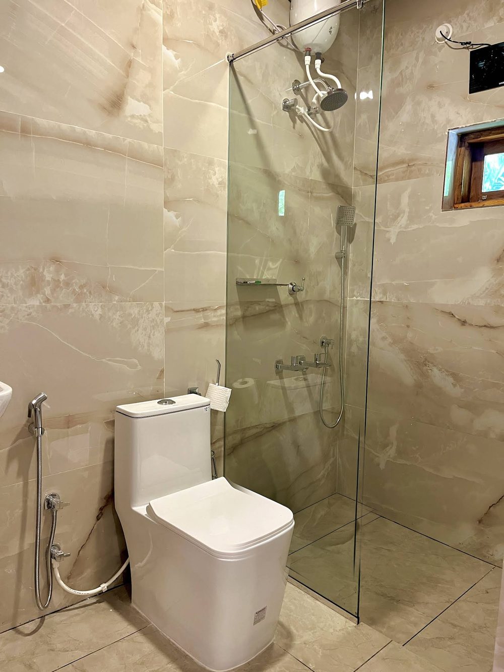 A bathroom at Olam, lined in onyx-effect tile with a glass shower screen