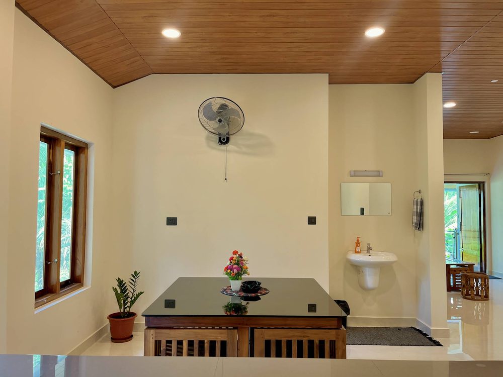 The dining room at Olam: a black granite table under a wall fan, with fresh flowers