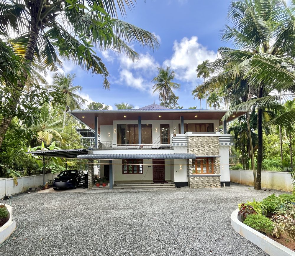 The front of the house at Olam, seen across the gravel court between coconut palms