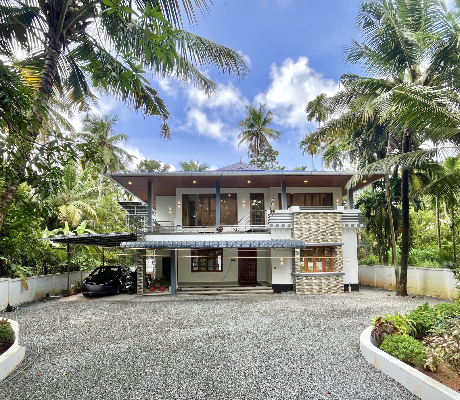 The front of the house at Olam, seen across the gravel court between coconut palms