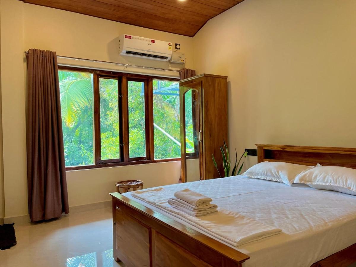 Airy bedroom with a teak bed and tall windows onto the greenery