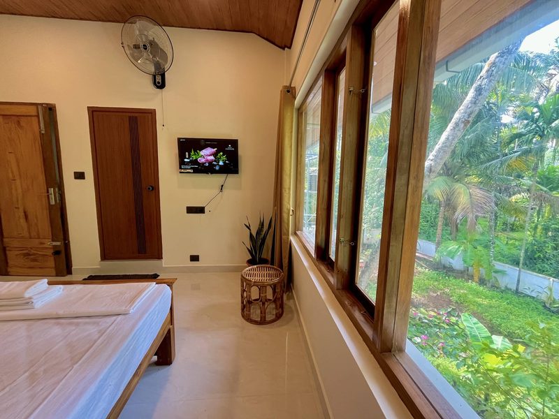 Bedroom with a corner wall of teak casement windows onto the palms