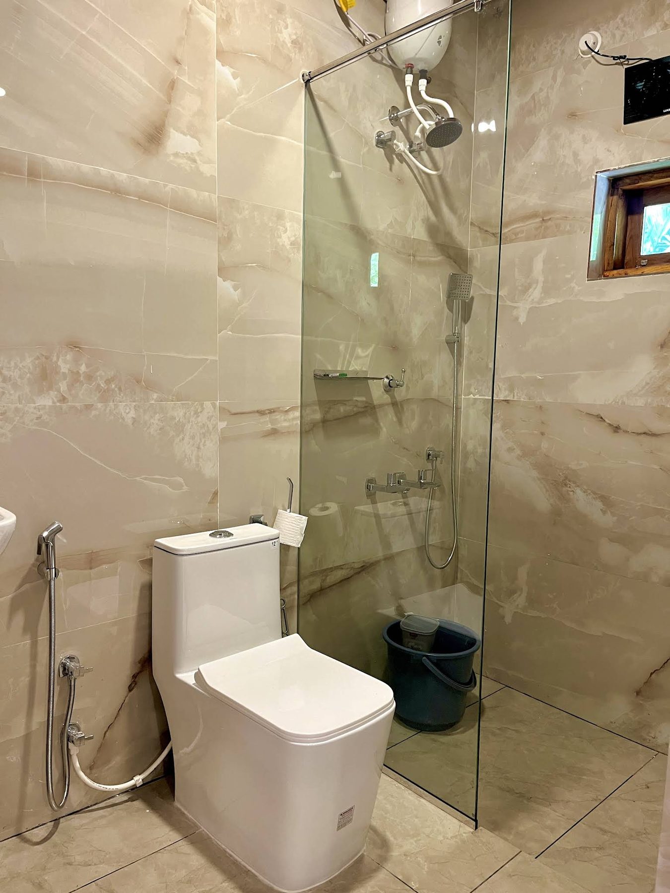 Guest bathroom with a frameless glass shower screen and beige onyx-look tile