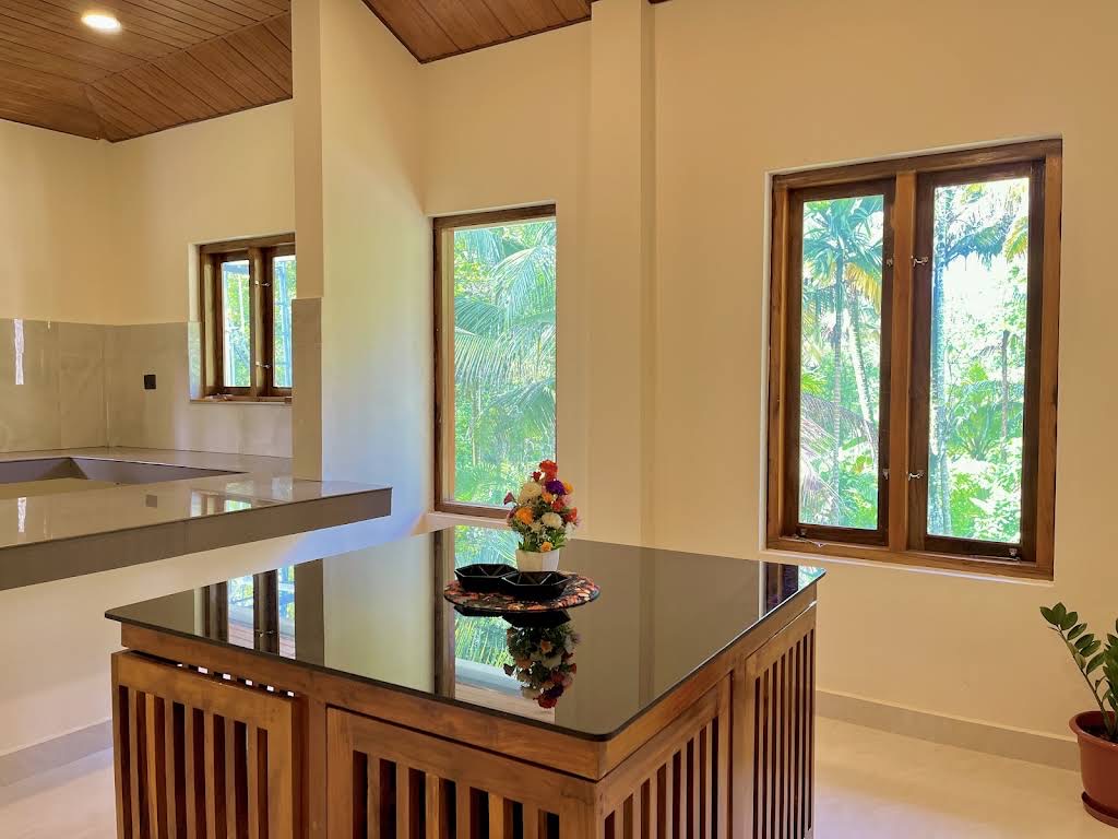 Kitchen island in grey quartz beside teak-framed windows